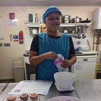 Danielle in a blue apron and hat, mixing ingredients in a bowl.