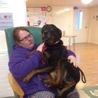 Lou sitting in a chair with Trixie on her lap. Trixie is a black dog about half the size of Lou.