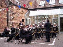 A band sat outside in the parking area, in a semicircle around the conductor.
